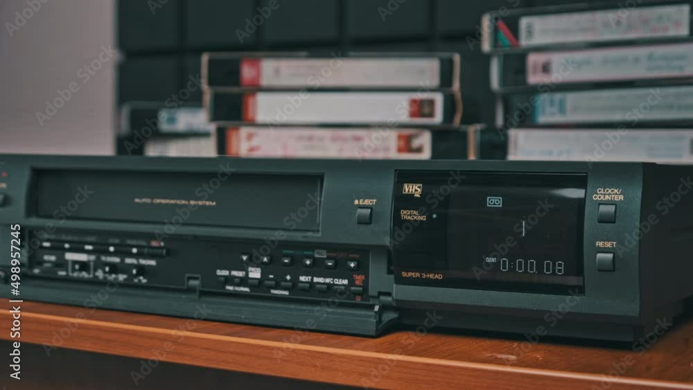 Eject VHS tape cassette from VCR player. Man pulls out VHS from vintage