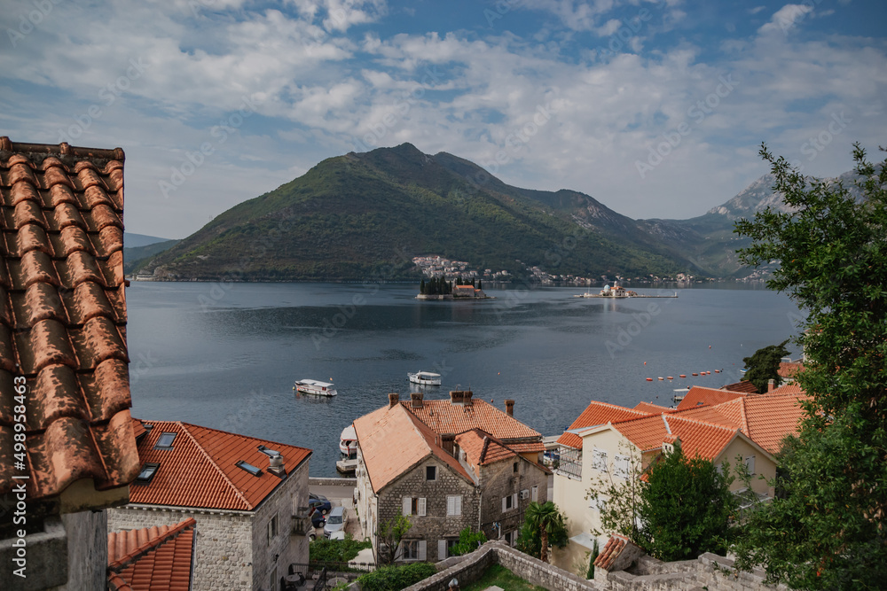 Scenic panorama view of the historic town of Perast at famous Bay of Kotor with mountains on a beautiful sunny day with blue sky and clouds in summer, Montenegro, southern Europe