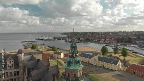 Cinematic 4K aerial drone dolly out shot of Kronborg Slot Castle, one of UNESCO's World Heritage sites, Helsingør city and docking ferry in Denmark photo