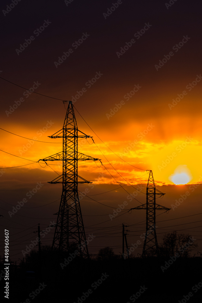 Fototapeta premium High voltage power line at sunset. Silhouettes of the metal pillars