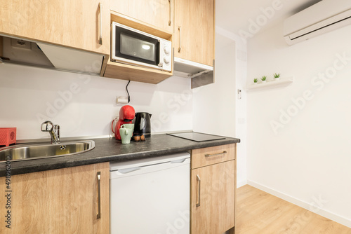 Kitchen with dark gray countertops, wood cabinets, and built-in white appliances in an urban vacation rental apartment
