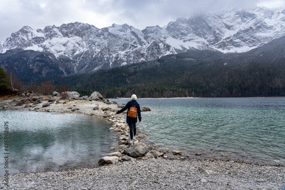 beautiful Eibsee mountain lake in Grainau Germany with Zugspitze mountains in the background tourist woman walking on rock pathway