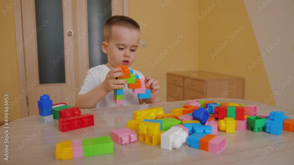 Funny baby boy playing with colorful building blocks, having fun. Cute little child playing with toy plastic constructor at home. Assembling plastic toy bricks, education toys. Funny baby boy playing with colorful building blocks, having fun. Cute little child playing with toy plastic constructor at home. Assembling plastic toy bricks, education toys.
