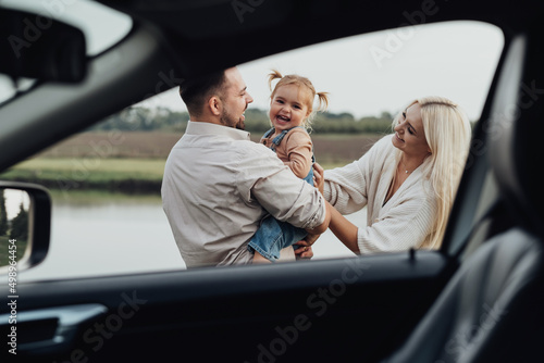 View Through Window Inside of Car, Happy Young Family, Mom and Dad with Their Little Daughter Having Fun Together and Enjoying Weekend Outside the City