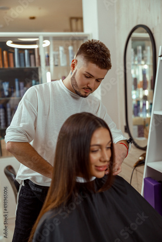 Young woman getting a haircut by professional male hairdresser at beauty salon. Haircut, hair care