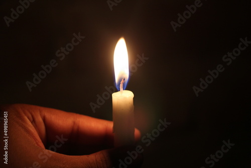 Holding burning candle in the darkness