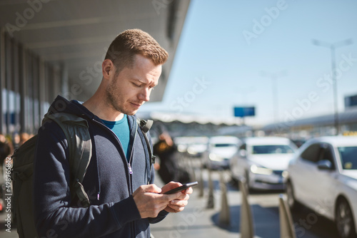 Vászonkép Man holding smartphone and using mobile app against a row of taxi cars