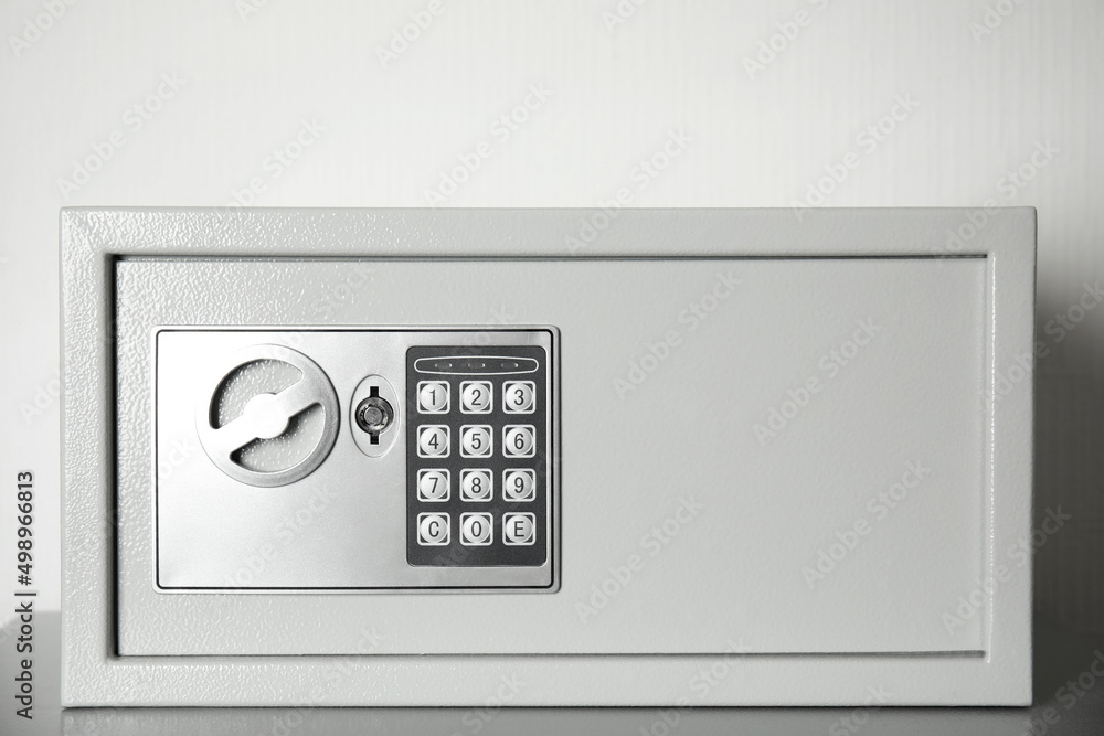 Closed steel safe on grey table against light background Closed steel safe on grey table against light background
