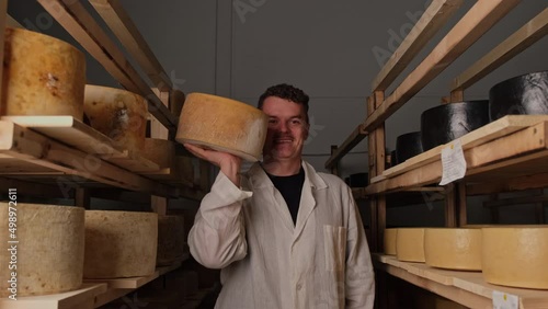 The cheese maker stands between the shelves 