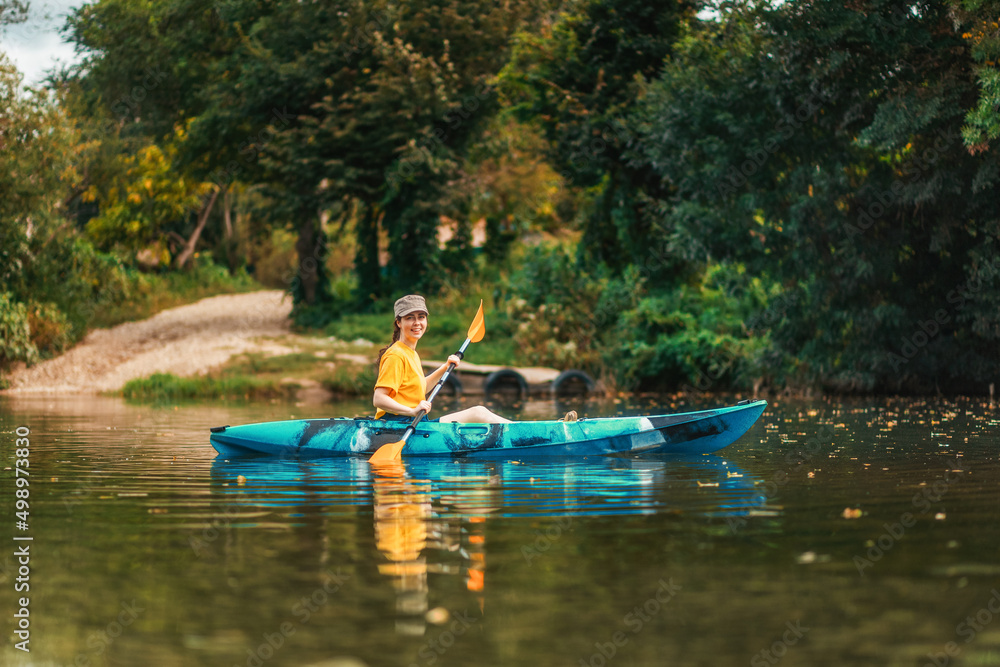 World Tourism Day. Happy smiling girl floating in blue kayak at river. Copy space. The concept of kayaking