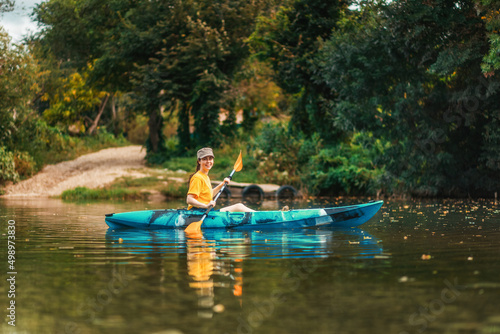 World Tourism Day. Happy smiling girl floating in blue kayak at river. Copy space. The concept of kayaking