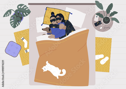A bedroom morning scene, a young lesbian couple spooning in bed with their pets, a dog and a cat