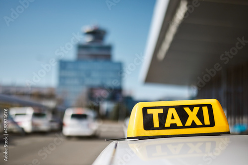 Selective focus on taxi sign on roof of car against airport terminal. .