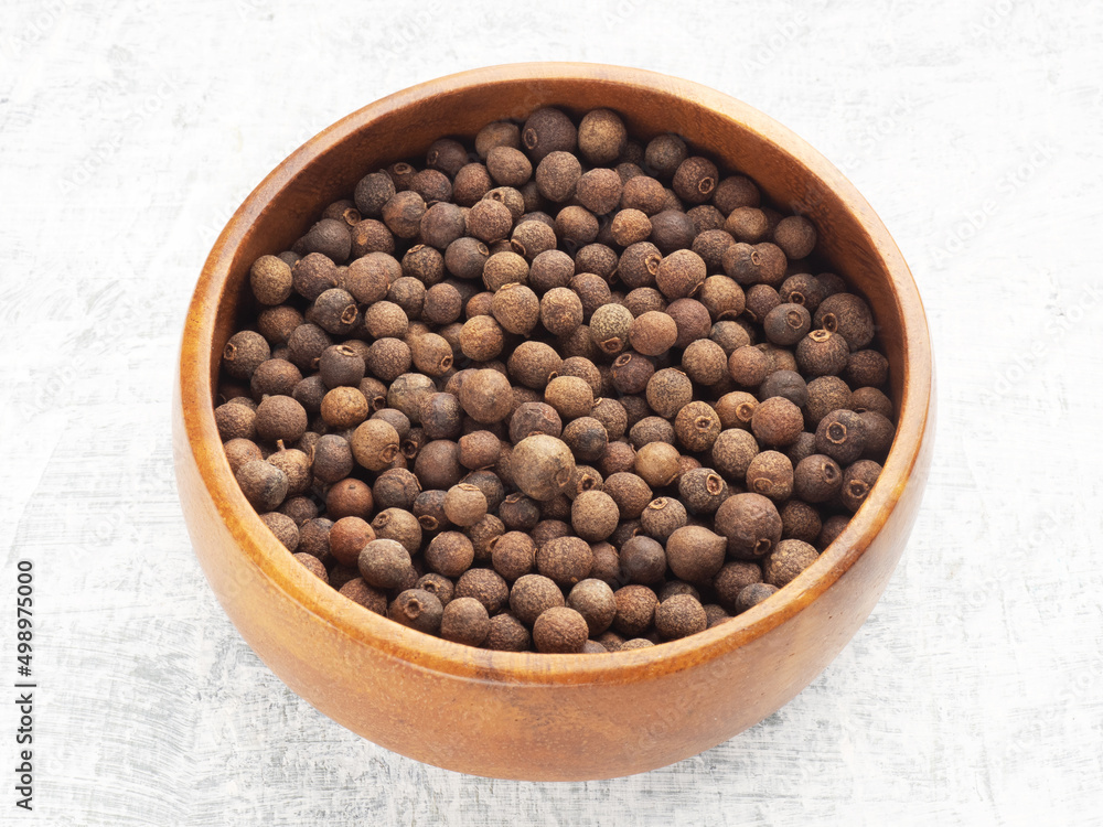 Spice Allspice (Jamaica pepper, Pimento) in wooden bowl on white concrete background. Macro. Healthy eating concept Spice Allspice (Jamaica pepper, Pimento) in wooden bowl on white concrete background. Macro. Healthy eating concept