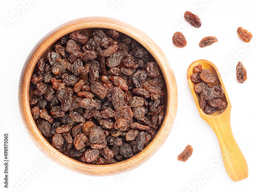 Raisin in wooden bowl and scoop, bunch isolated on white. Macro. Healthy food concept