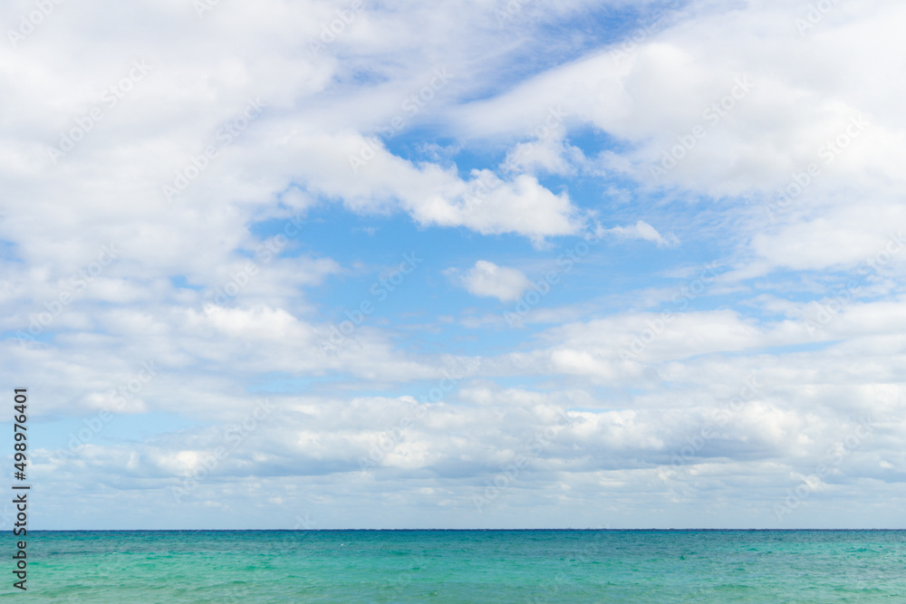 View of the cloudy sky and a strip of turquoise sea. Sea horizon. The horizon where the cloud sky meet the water.