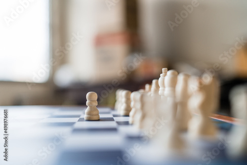 Fotografiet Close up white pawn chess piece standing on the chessboard outstanding from the others on the chessboard