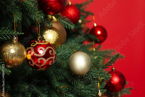 Beautifully decorated Christmas tree against red background  closeup