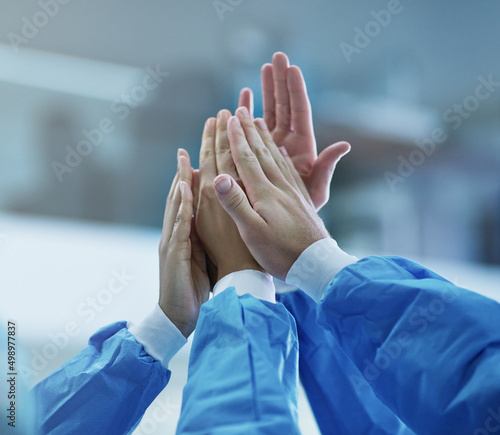 Cooperation for a successful operation. Cropped shot of a team of surgeons giving each other a high five. photo