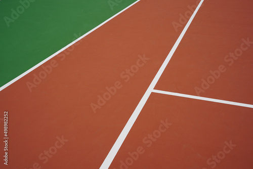 Lignes blanches sur terrain de tennis vert et orange