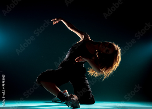 Modern dance performer practicing modern dance on dark wall photo