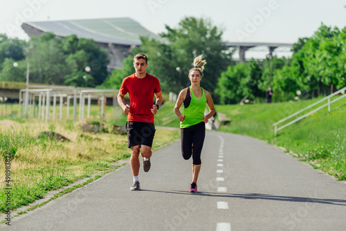Full-length front view of an attractive caucasian couple running together in a park on a sunny day..