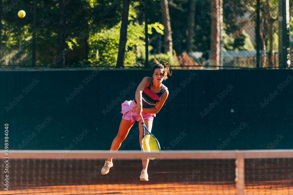 Obraz premium Professional equipped female tennis player serving the tennis ball on a sunny day