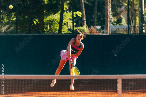 Professional equipped female tennis player serving the tennis ball on a sunny day © qunica.com