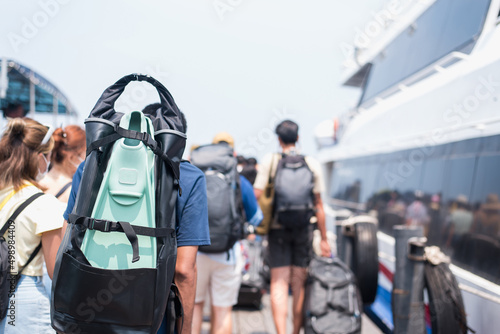 Traveler man with diving fins and travel bag walking the boat, from the port, traveland vacation concept.