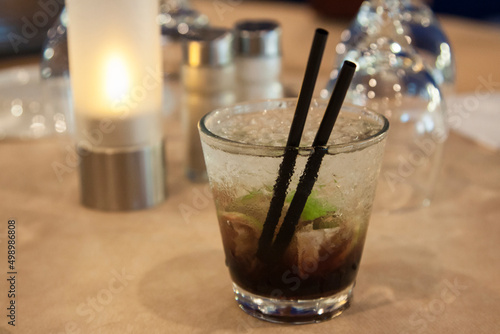 Caipirinha, brazilian authentic national cocktail made with cachaca, sugar cane hard liquor, in the wet glass with straws on a table