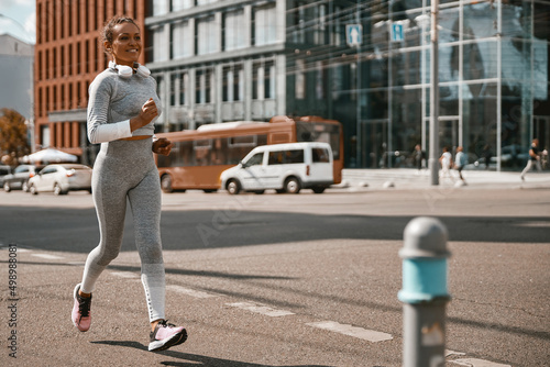 Fit woman with a mask running along the city street. Healthy lifestyle, Covid 19. Full length © Yaroslav Astakhov