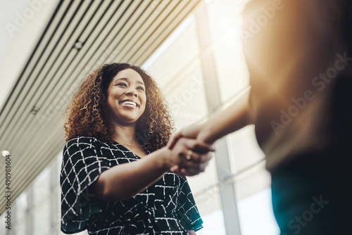 Welcome to the company. Low angle shot of an attractive young businesswoman shaking hands with an associate in a modern workplace.