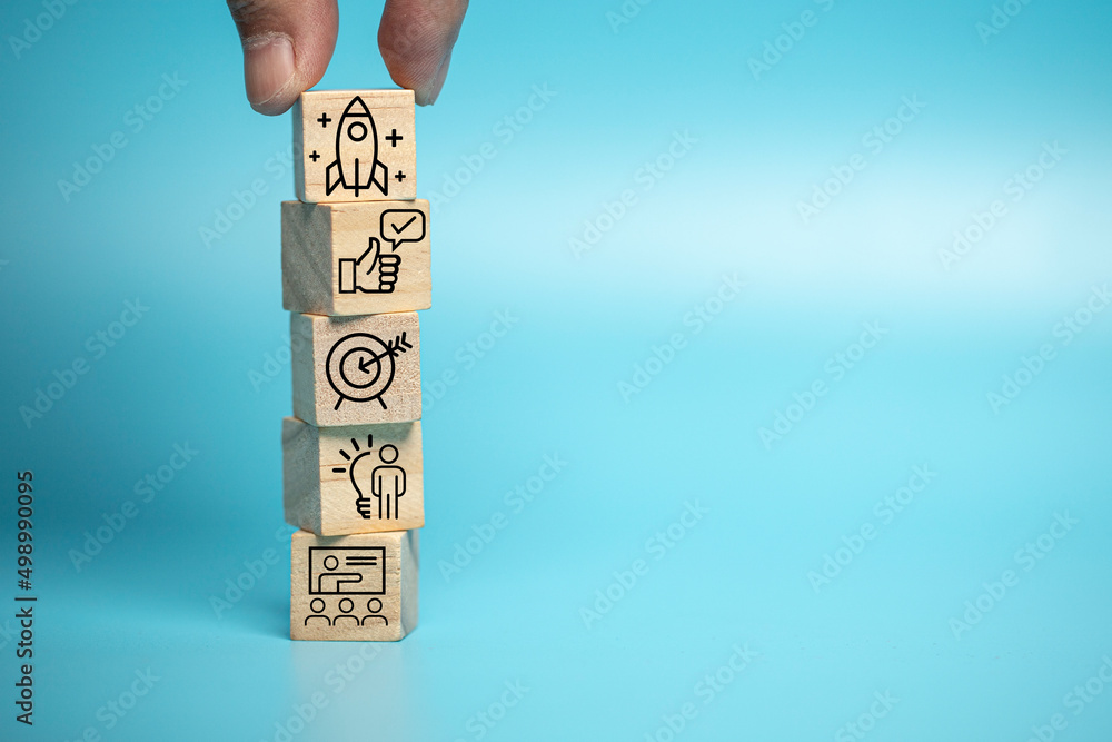 Businessman puts a wooden block of business symbols. Marketing and product planning ideas, startups, product manufacturing orientations. - obrazy, fototapety, plakaty 