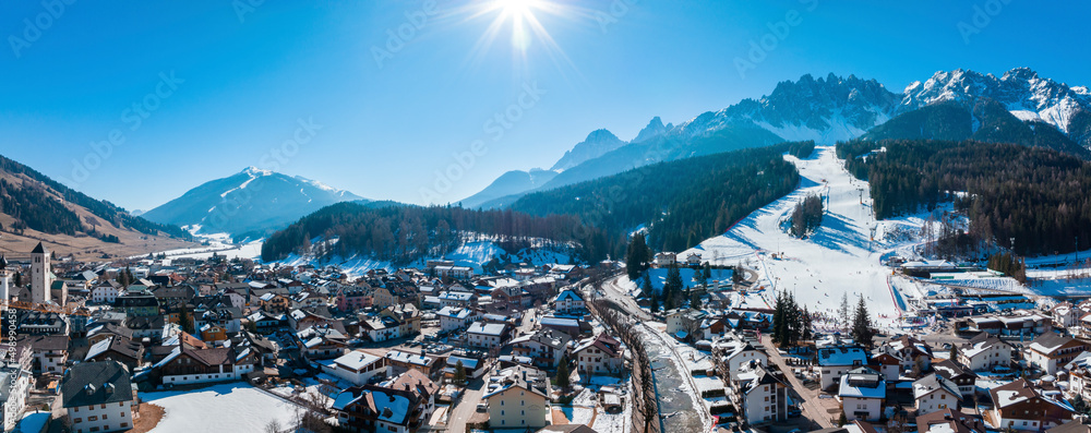 Panoramic view of sun shining over mountain range and townscape during winter