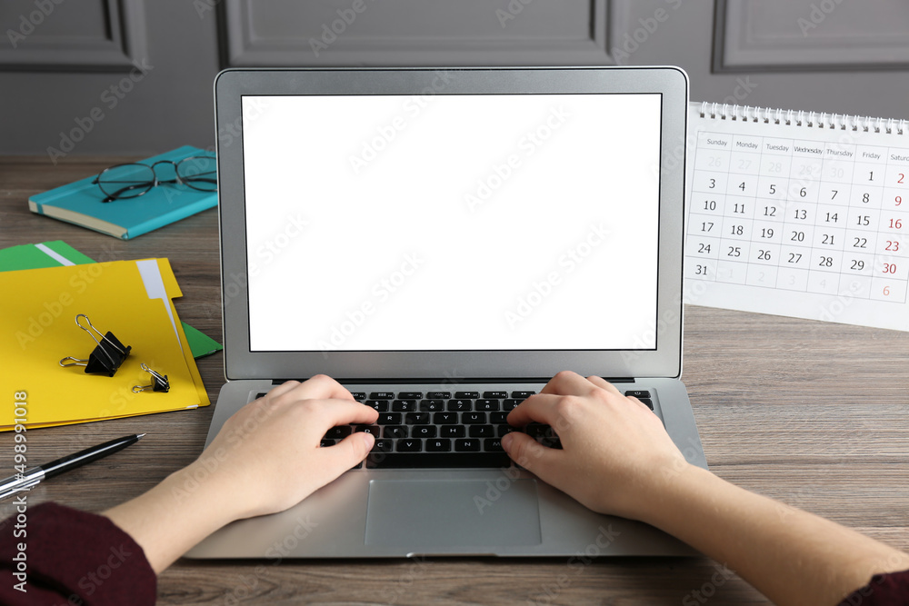 Fototapeta premium Woman using laptop for online studying at wooden table, closeup. Distance learning