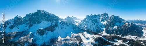 Panoramic view of snow covered mountain range against blue sky on a sunny day