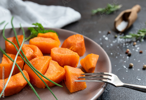 Roasted sweet potatoes with spices on a dark table close-up