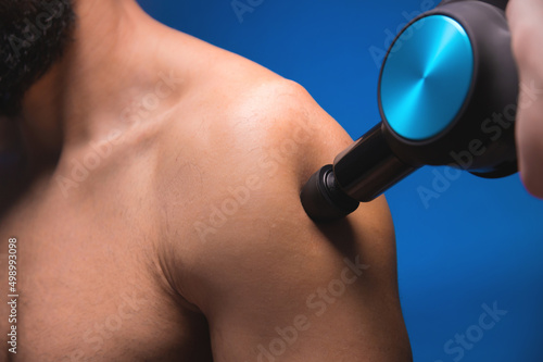 Cuadro en lienzo Close-up Bearded caucasian man getting percussion shoulder massage by a massager in a professional massage parlour