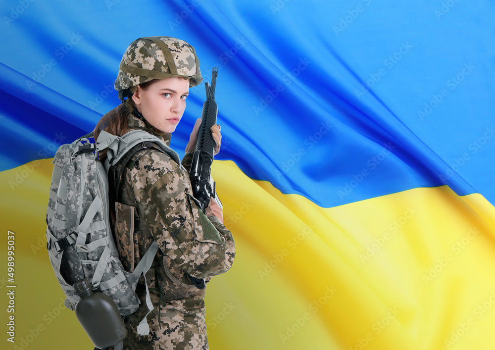 Fototapeta premium Armed soldier in military camouflage uniform and Ukrainian flag on background, space for text. Stop war