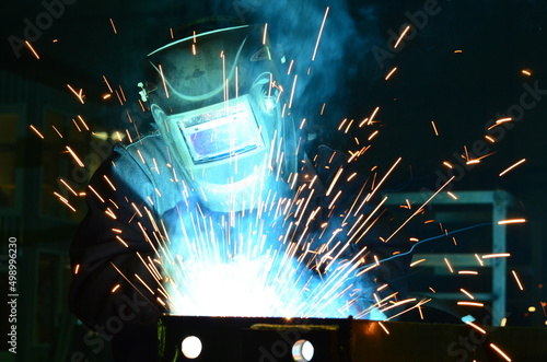 Workers wearing industrial uniforms and Welded Iron Mask at Steel welding plants, industrial safety first	