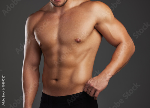 Shredded. Cropped shot of an unrecognizable and athletic young man posing shirtless in studio against a dark background.