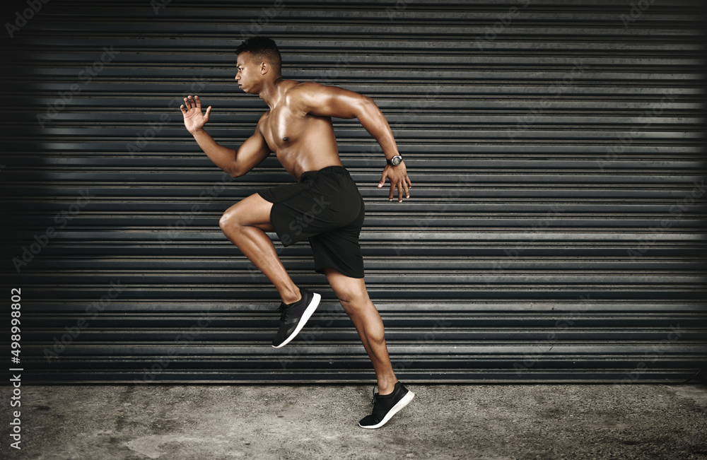 The key is to keep challenging yourself. Shot of a fit and shirtless young man running.