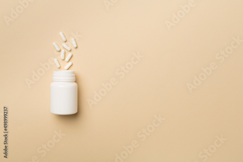White bottle with pills on color background