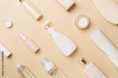 Different cosmetic bottles and container on color background, top view