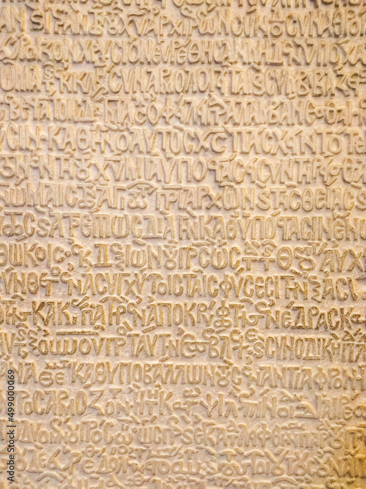 Ancient Greek writing in stone. A wall with ancient Greek letters. Historical archaeological background