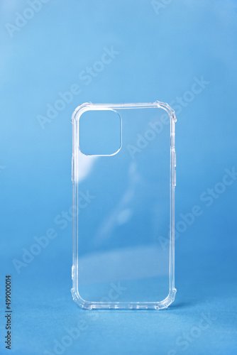 Close-up of a transparent silicone case for a smartphone on a blue background, vertical image.