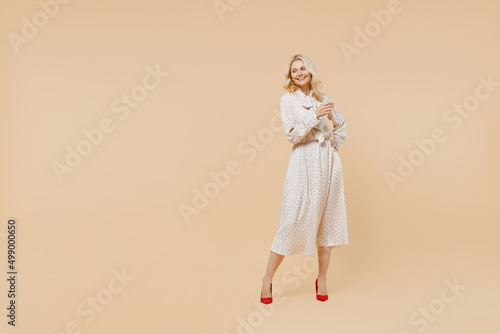 Full size body length blithesome delight ecstatic fun elderly gray-haired blonde woman lady 40s years old wear pink dress looking down posing isolated on plain pastel beige background studio portrait