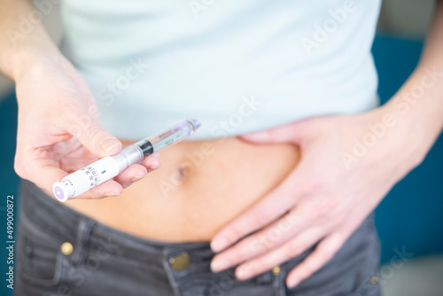 Close-up of the hands and stomach of a diabetic woman giving herself.