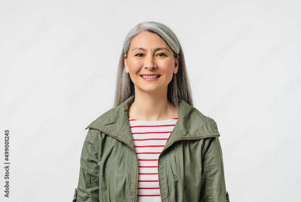 Closeup cropped portrait of happy mature middle-aged woman mother grandmother with grey hair in casual clothes looking at camera isolated in white background Closeup cropped portrait of happy mature middle-aged woman mother grandmother with grey hair in casual clothes looking at camera isolated in white background