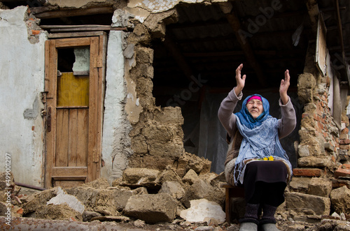 A woman prays in front of a destroyed house during the war. Ukrainian woman on the ruins of a war-torn house. War in Ukraine. Bombardment of Ukrainian cities. Ukrainian refugees. photo